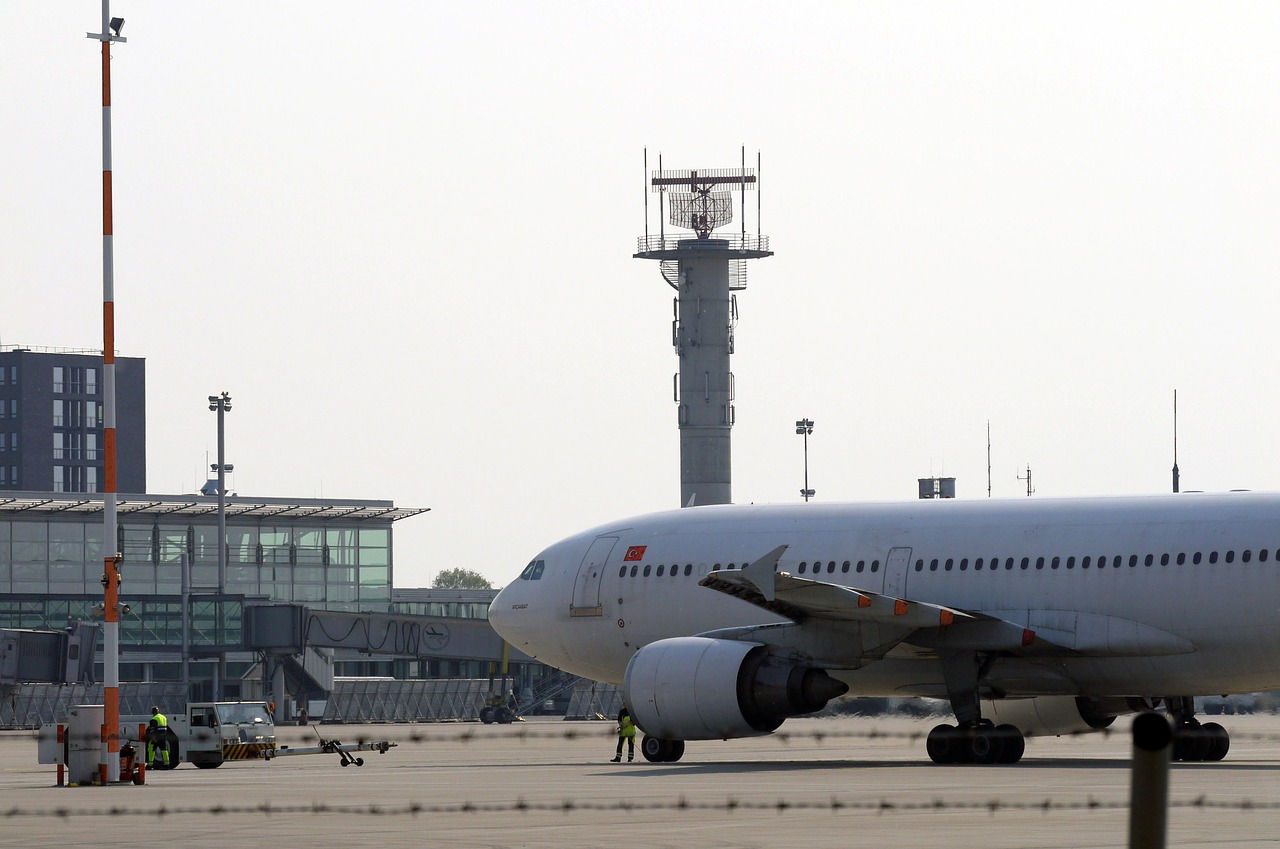 An airliner at an airport with radar tower in the background